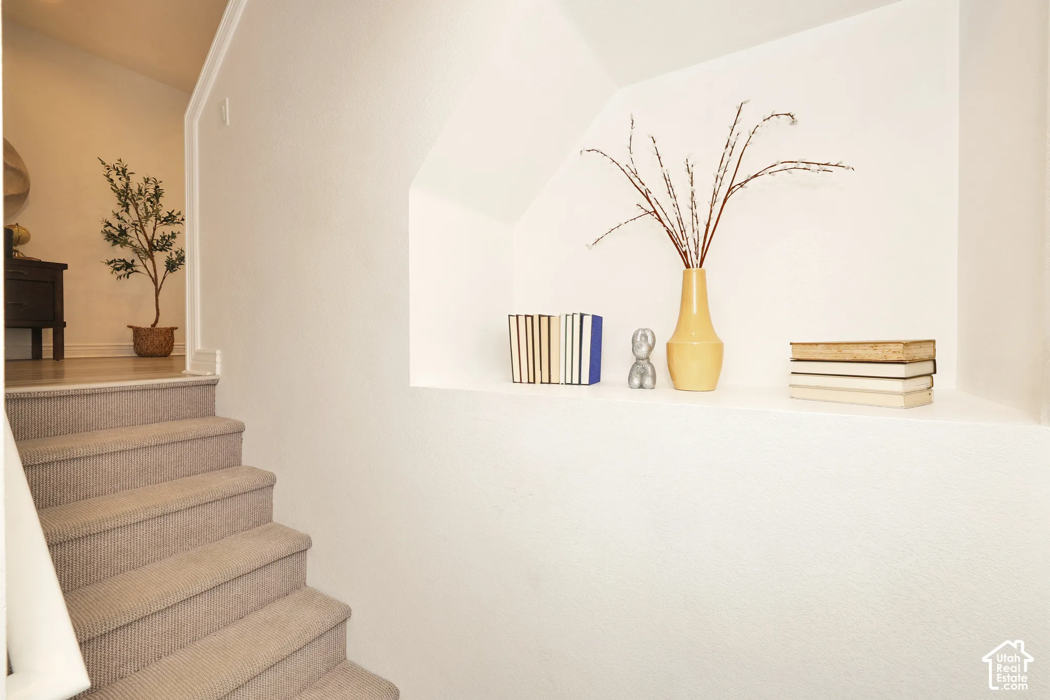 Recessed wall niche with smooth finished edges and carpeted staircase featuring a matching neutral tone