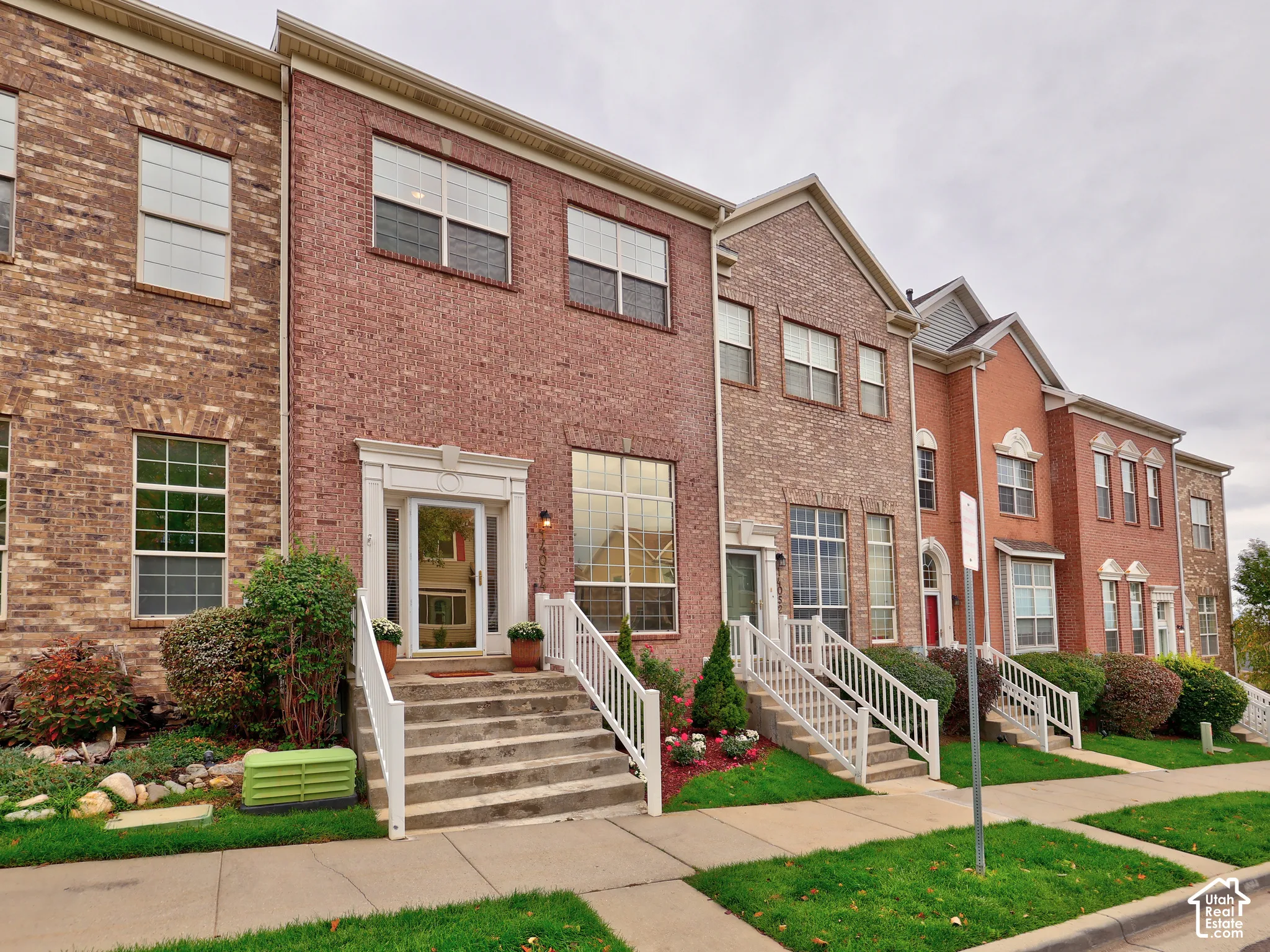 Multi-level brick exterior featuring multi-pane windows, elevated entryway stairs, and white railing systems
