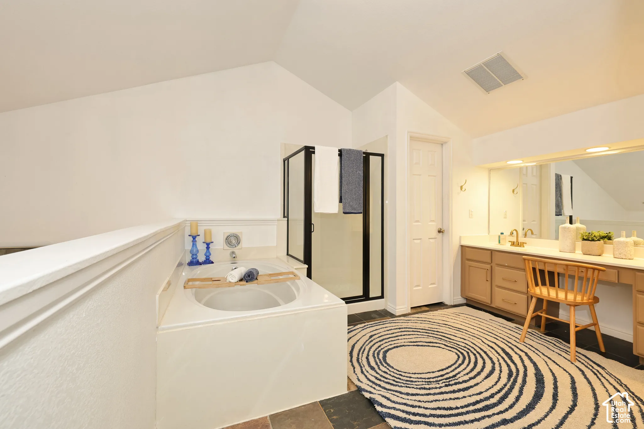 Built-in soaking tub, walk-in shower with black-frame enclosure, vanity with integrated cabinetry, and full-width vanity mirror