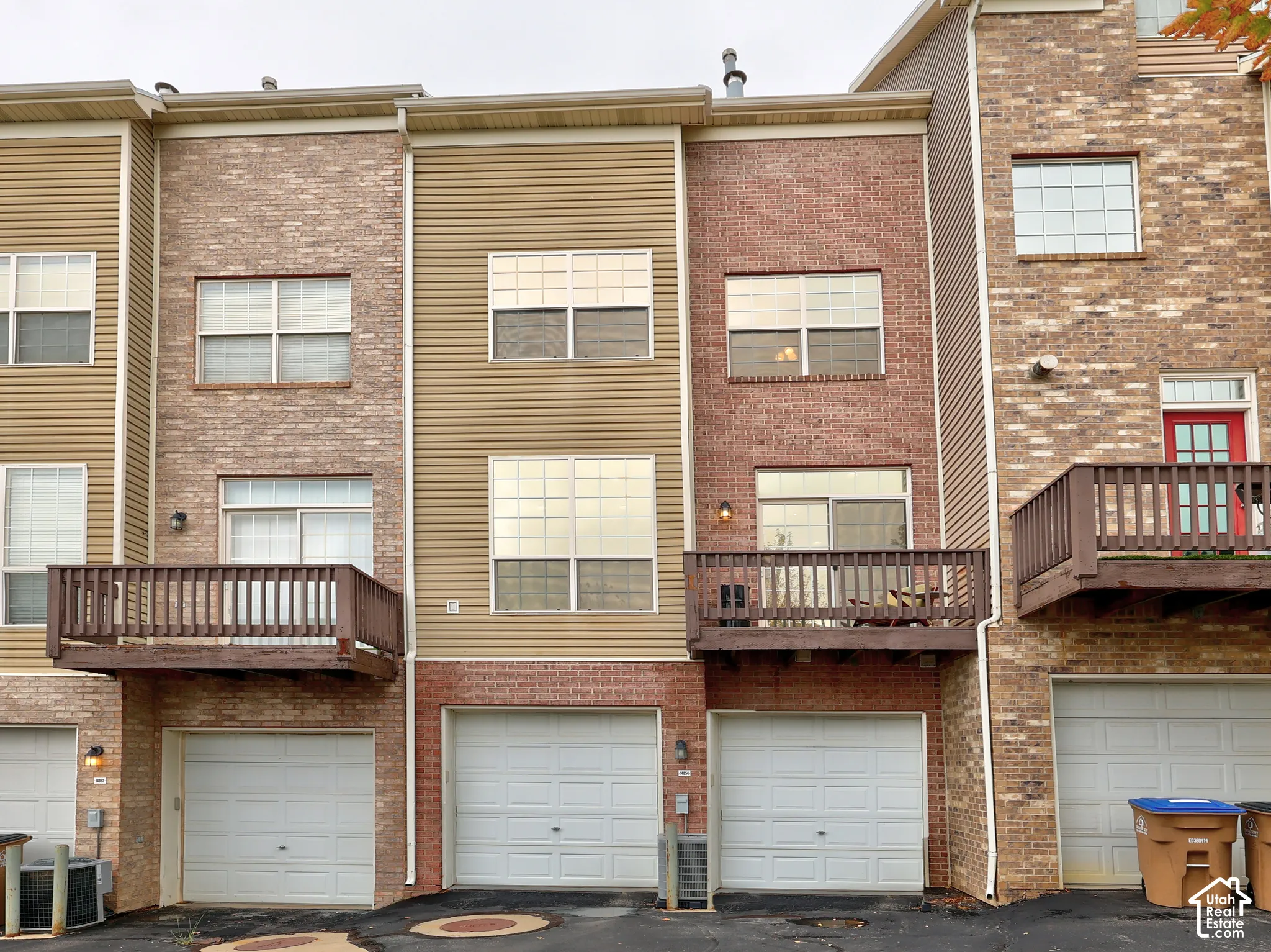 Multi-level exterior featuring a brick and vinyl siding facade, integrated multi-car garage, and elevated wooden decks
