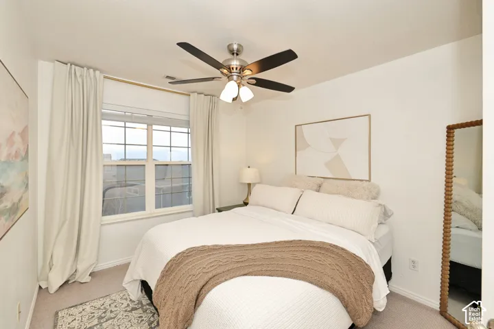 Neutral-toned room featuring a multi-light brushed-nickel ceiling fan and a large window with a multi-pane grid