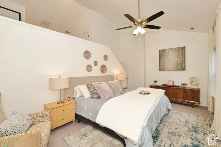 Vaulted ceilings featuring a central ceiling fan with integrated lighting and carpeted flooring