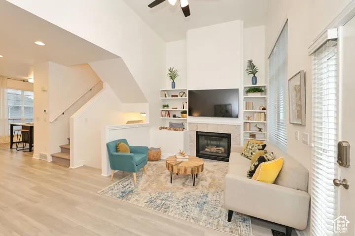 Living area featuring vaulted ceilings, a fireplace with a stone-surround hearth, built-in shelving, wood-finish flooring, and recessed lighting