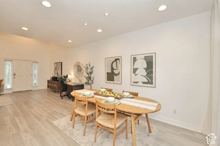 Open-concept area featuring high ceilings, wood-finish flooring, recessed lighting, and a multi-panel front door with dual sidelights