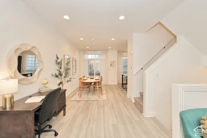 Open-concept floor plan featuring wood-finish flooring, recessed lighting, sliding glass doors, and a staircase with a glass-paneled railing
