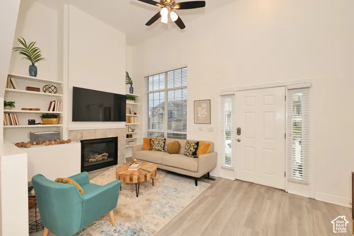 Vaulted ceilings, floor-to-ceiling windows, stone-surround fireplace, built-in shelving, and wood-finish flooring