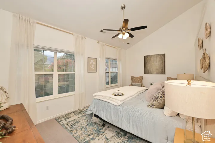 Vaulted ceiling featuring a central brushed-nickel ceiling fan with integrated lighting and dual grid-pane windows