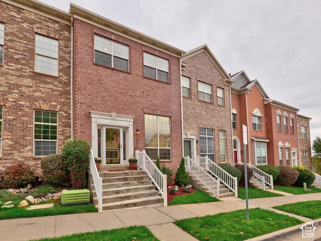 Multi-level brick exterior featuring multi-pane windows, elevated entryway stairs, and white railing systems