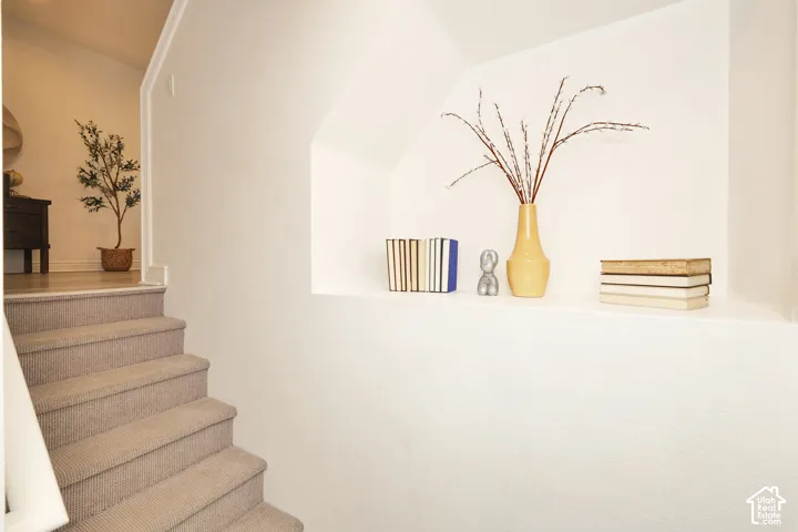 Recessed wall niche with smooth finished edges and carpeted staircase featuring a matching neutral tone