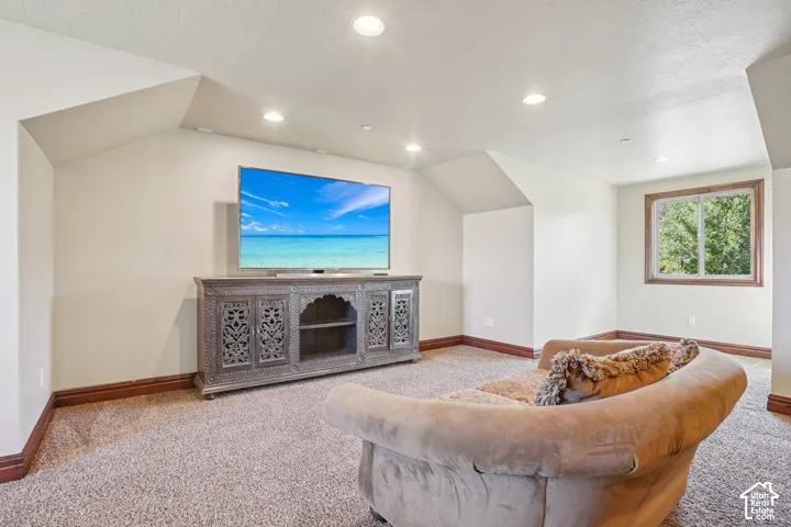 Recessed lighting, sloped ceiling details, and neutral carpet flooring