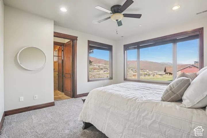 Expansive windows, ceiling fan, recessed lighting, wood-finish trim, and carpeted flooring