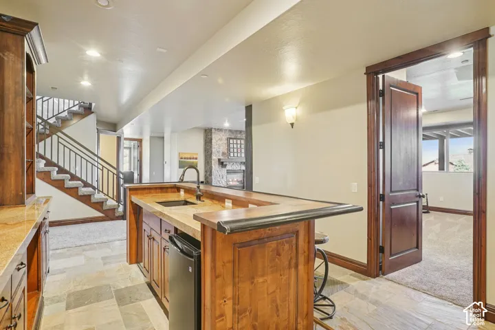 Built-in wet bar with wood cabinetry, stone countertops, and integrated beverage refrigerator