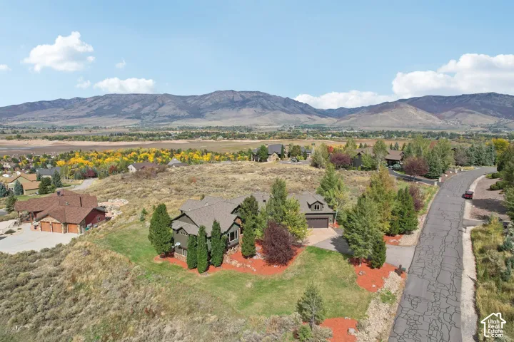 Mountainous backdrop, residential neighborhood, paved road, established landscaping, mature trees