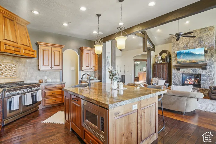 Gourmet kitchen with wood cabinetry, stainless steel appliances, and a large central island with a stone countertop