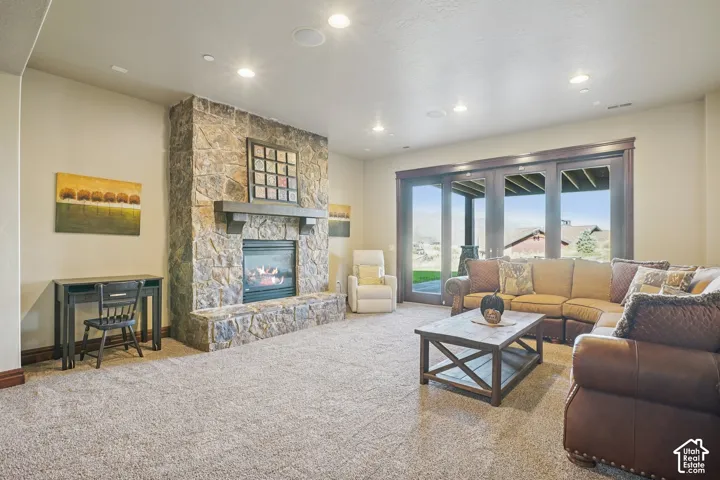 Spacious living area featuring a stone fireplace with a substantial mantel, recessed lighting, and expansive glass doors leading to an outdoor space