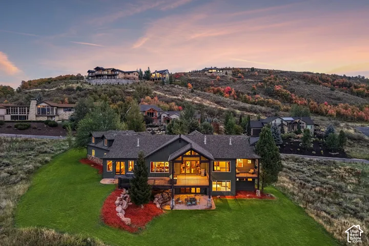 Sloped-lot architecture featuring multiple terraces, a stone patio, and an expansive lawn