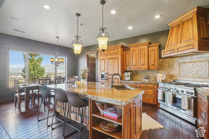 Gourmet kitchen featuring wood cabinetry, stainless steel range, and a large island with an integrated sink