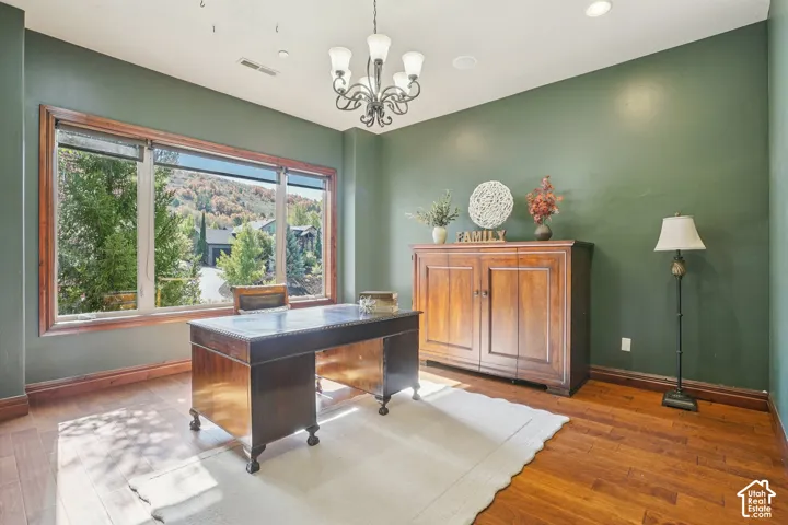 Hardwood flooring, painted walls, large window with outdoor scenery, recessed lighting, and a chandelier