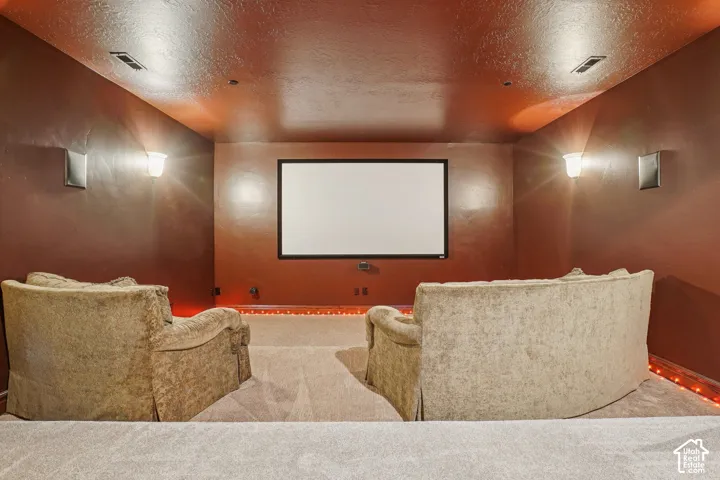 Dedicated media room featuring a large projector screen, wall-mounted speakers, and recessed ceiling lights