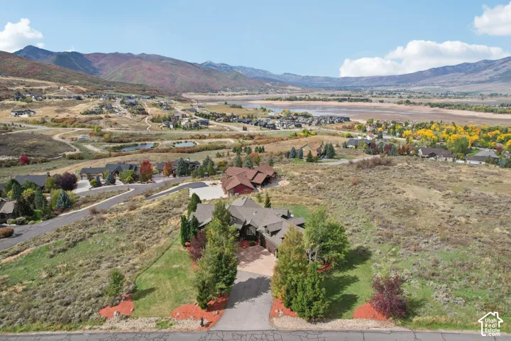 Expansive property featuring a paved driveway, mature trees, and a surrounding natural landscape