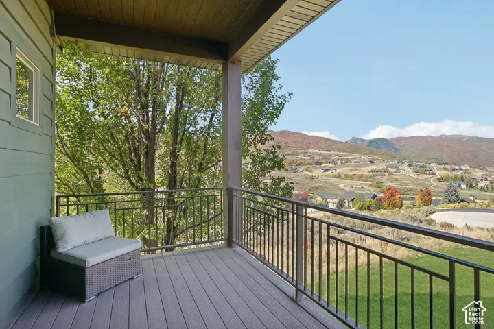 Covered balcony featuring wood-finish decking and a black metal railing
