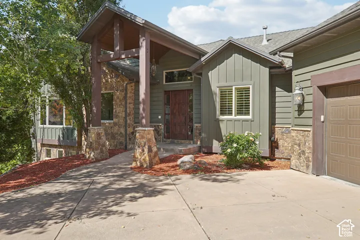 Wood-clad exterior with stone accents, covered entry, and attached garage