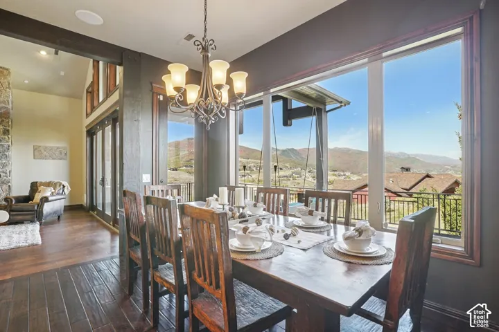 Wood-finish flooring throughout, wrought iron chandelier, expansive windows, mountain scenery, and glass panel doors