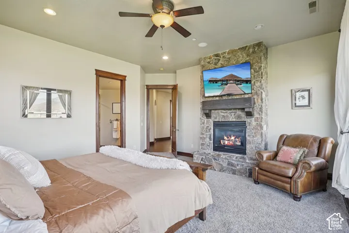 Stone-clad fireplace with a wood mantel, recessed lighting, and a ceiling fan