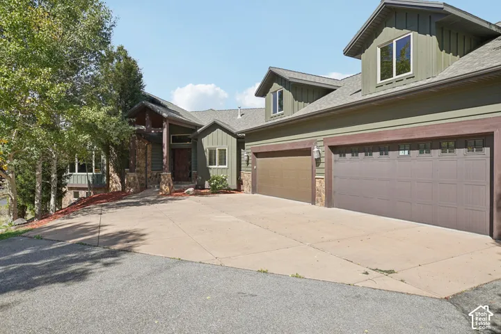 Multi-car garage with panel-style doors, stone column accents, and dormer windows
