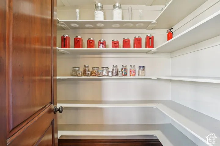 Extensive pantry featuring multiple white built-in shelves and a rich wood-paneled door