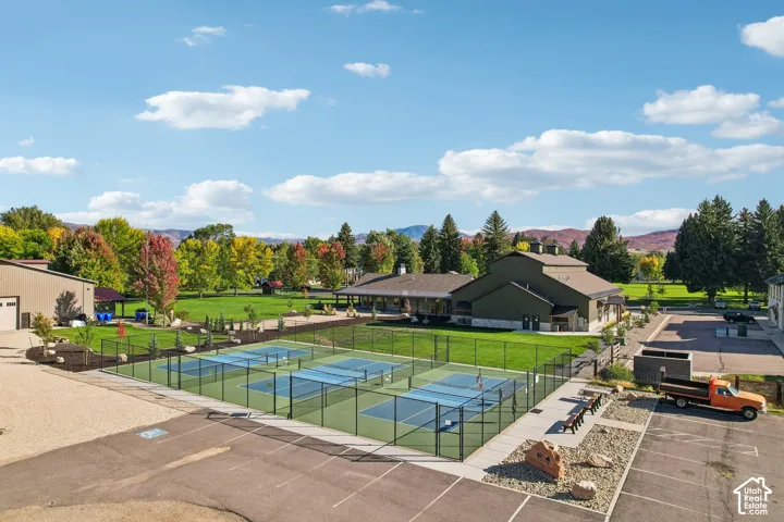 Multiple pickleball courts with black fencing, expansive green lawn, and mature trees