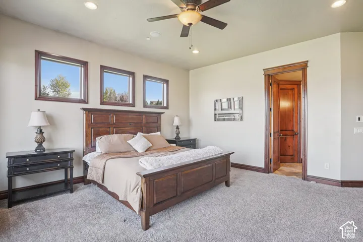 Plush carpet flooring, recessed lighting, ceiling fan, solid wood-paneled door, and three transom windows with wood trim