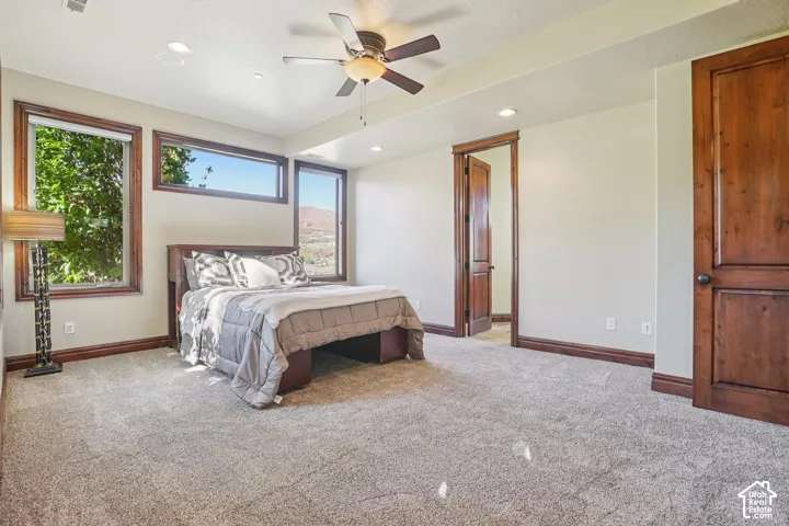 Carpeted room featuring a ceiling fan, recessed lighting, and multiple windows with wood trim