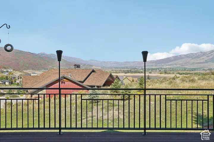 Expansive deck with black metal railing, offering broad mountain and valley scenery
