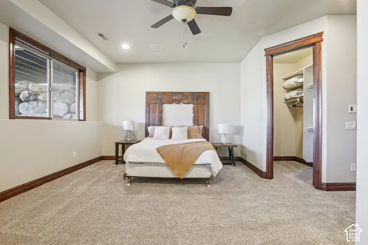 Plush carpet flooring, recessed lighting, ceiling fan, wood-trimmed egress window, and built-in closet shelving