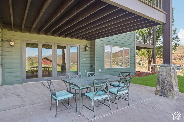 Expansive concrete patio with a full overhang, direct access through multi-panel glass doors, and a stone-clad structural support column