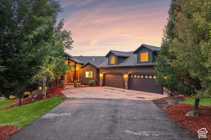 Multi-level home featuring a stone facade and a gray shingle roof