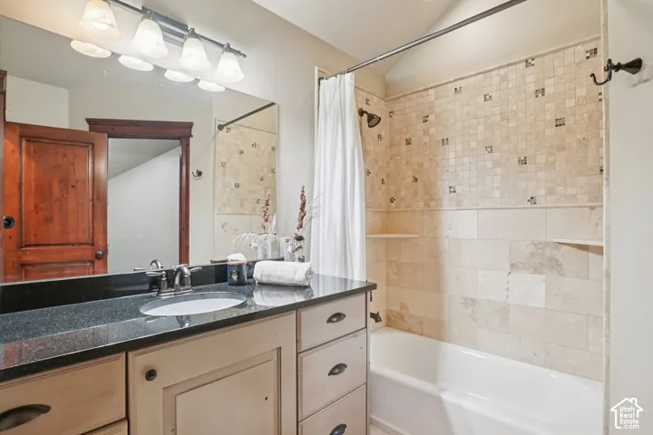 Bathroom featuring a vanity with an integrated sink, dark countertop, and light-toned cabinetry