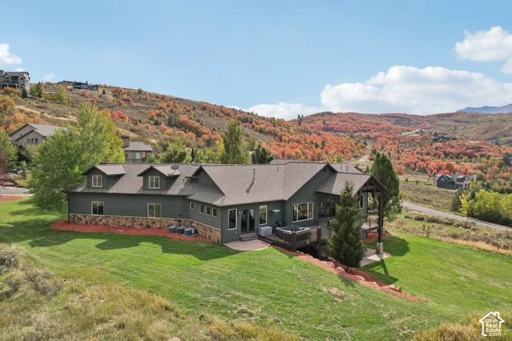 Expansive outdoor deck, multi-level property, stone foundation, dormer windows, and a structured outdoor living space