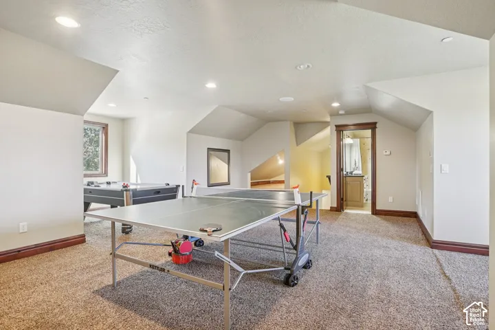Expansive carpeted room with multiple recessed lights and dormer windows