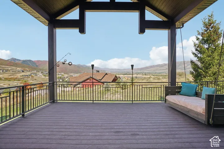 Expansive covered deck featuring composite decking, sturdy structural beams, and a black metal railing