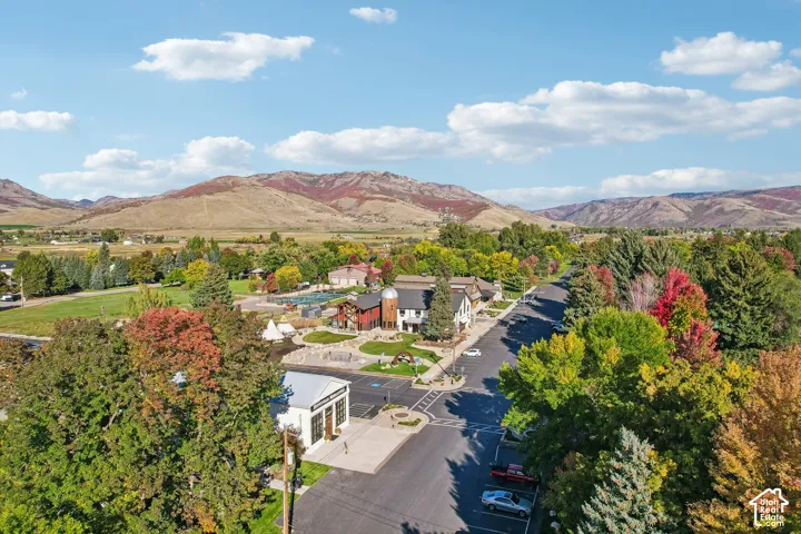 Mountain backdrop, mature trees with colorful foliage, paved roadways, residential structures, and commercial-style buildings