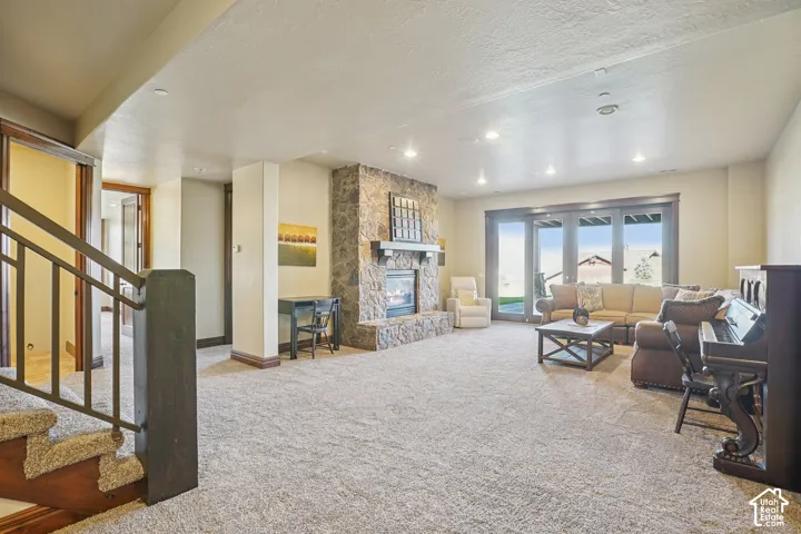Spacious living area featuring a stone-clad fireplace with a dark wood mantel, recessed lighting, and large glass paneled doors