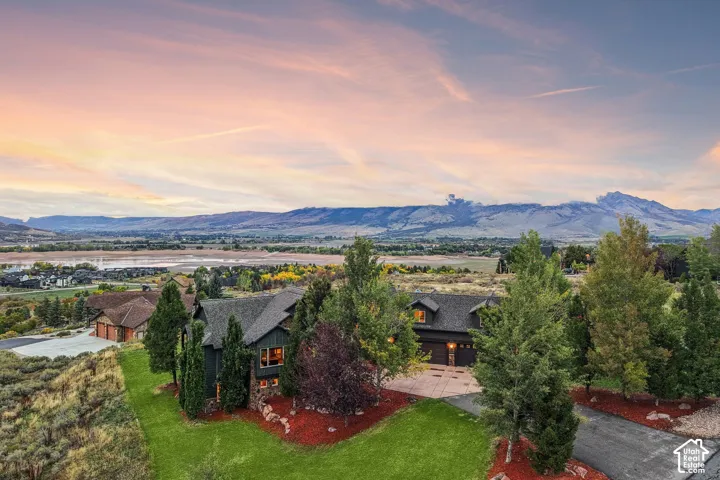Expansive property featuring a multi-level dark-toned residence with a stone-clad foundation, a paved driveway, and mature landscaping