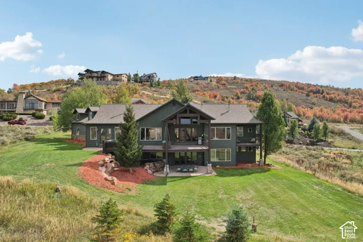 Multi-level exterior with extensive decking, a lower-level patio, and a sloped, manicured lawn