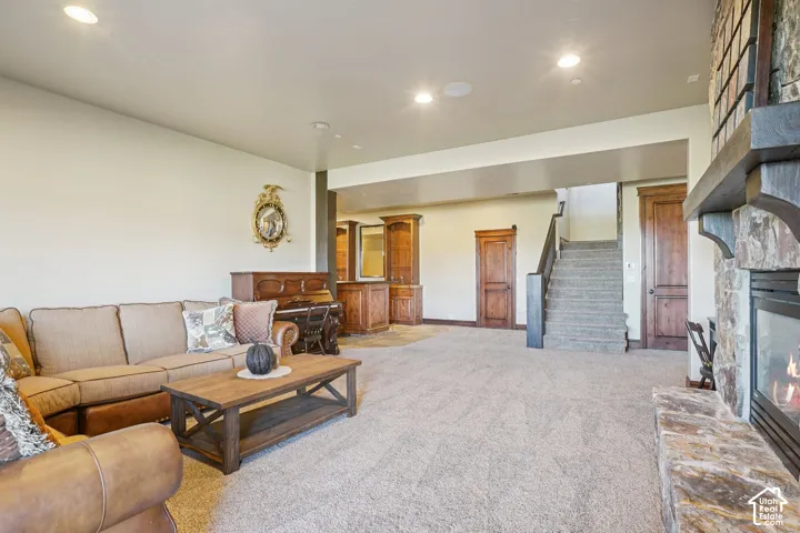 Recessed lighting, stone-clad fireplace with mantel, built-in wooden cabinetry, wooden doors, and carpeted flooring