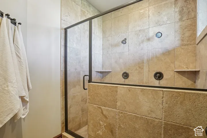 Glass-enclosed walk-in shower with dual shower heads, integrated wall niches, and stone tile surround