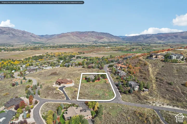 Expansive undeveloped lot with existing road access, surrounded by established residences, and framed by distant mountains and a valley