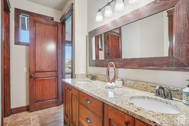 Double vanity with undermount sinks, granite-style countertop, and wood-finish cabinetry
