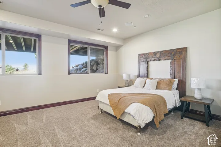 Carpeted room featuring two windows with dark wood trim, recessed lighting, and a ceiling fan
